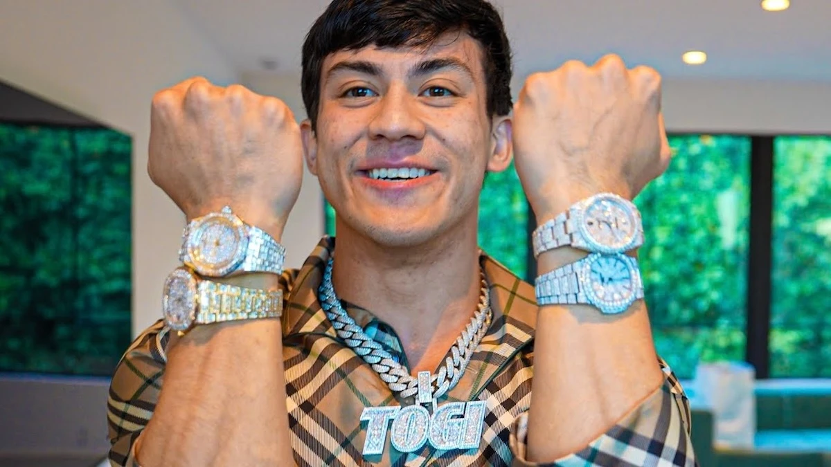 Togi, le Streamer américain montrant plusieurs montres de luxe et un collier lors d’un tournage en intérieur, style lifestyle et casino en ligne.