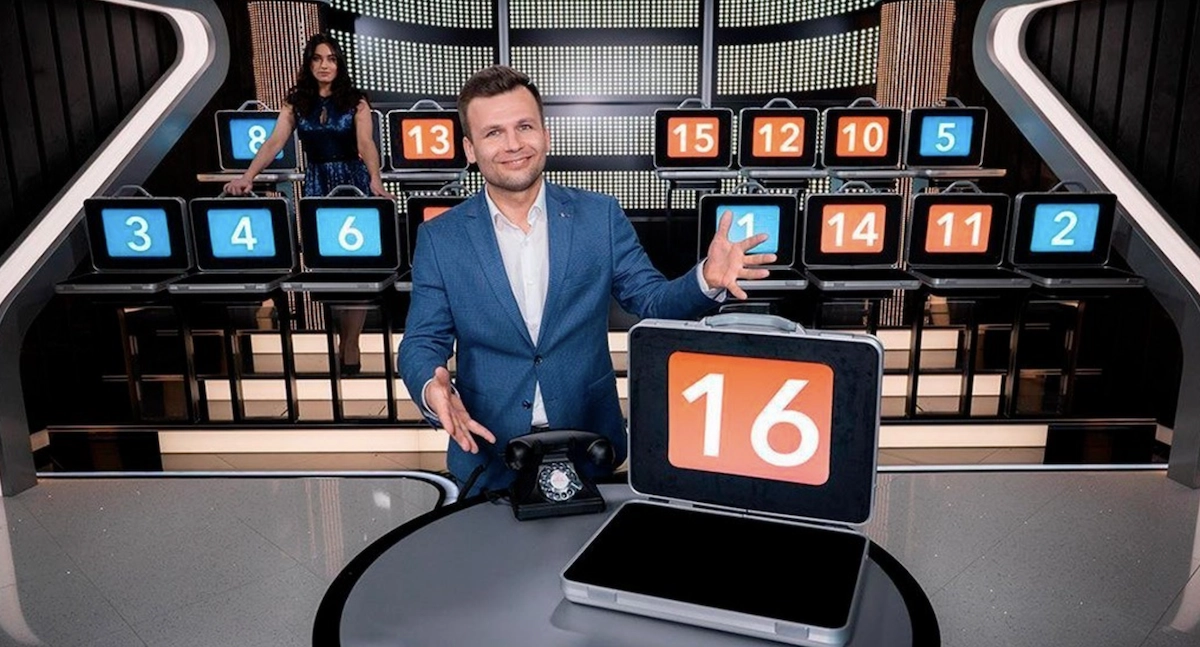 Plateau du jeu de casino live Deal or No Deal d&rsquo;Evolution avec un animateur devant plusieurs valises num&eacute;rot&eacute;es et un t&eacute;l&eacute;phone, inspir&eacute; du c&eacute;l&egrave;bre jeu t&eacute;l&eacute;vis&eacute; avec les gains cach&eacute;s dans les mallettes.