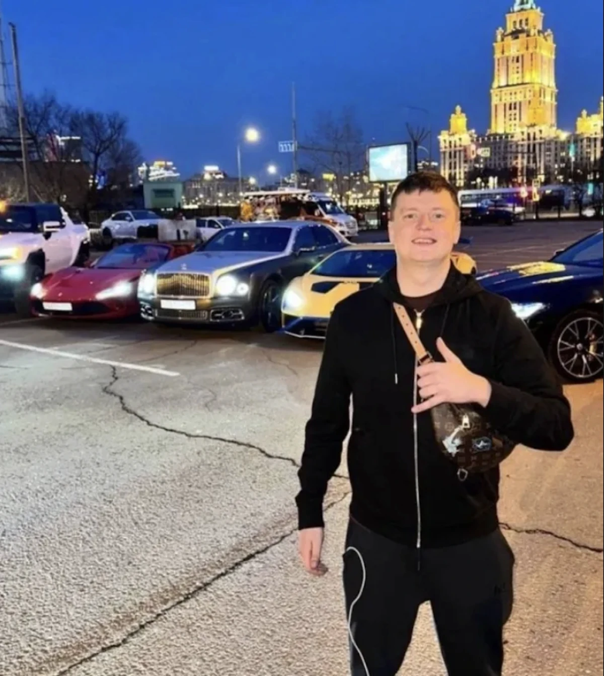 Mellstroy posant devant plusieurs voitures de luxe de nuit, image associée à son lifestyle argent et casino en ligne