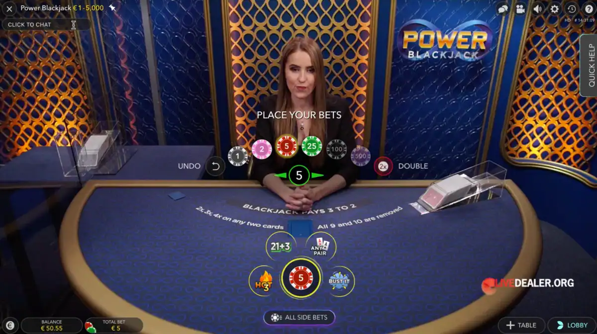Power Blackjack d’Evolution Gaming avec une croupière en direct assise derrière une table bleue, des jetons interactifs affichés à l’écran, des options de mise spéciales comme les multiplicateurs, et le logo Power Blackjack visible sur le mur du studio.
