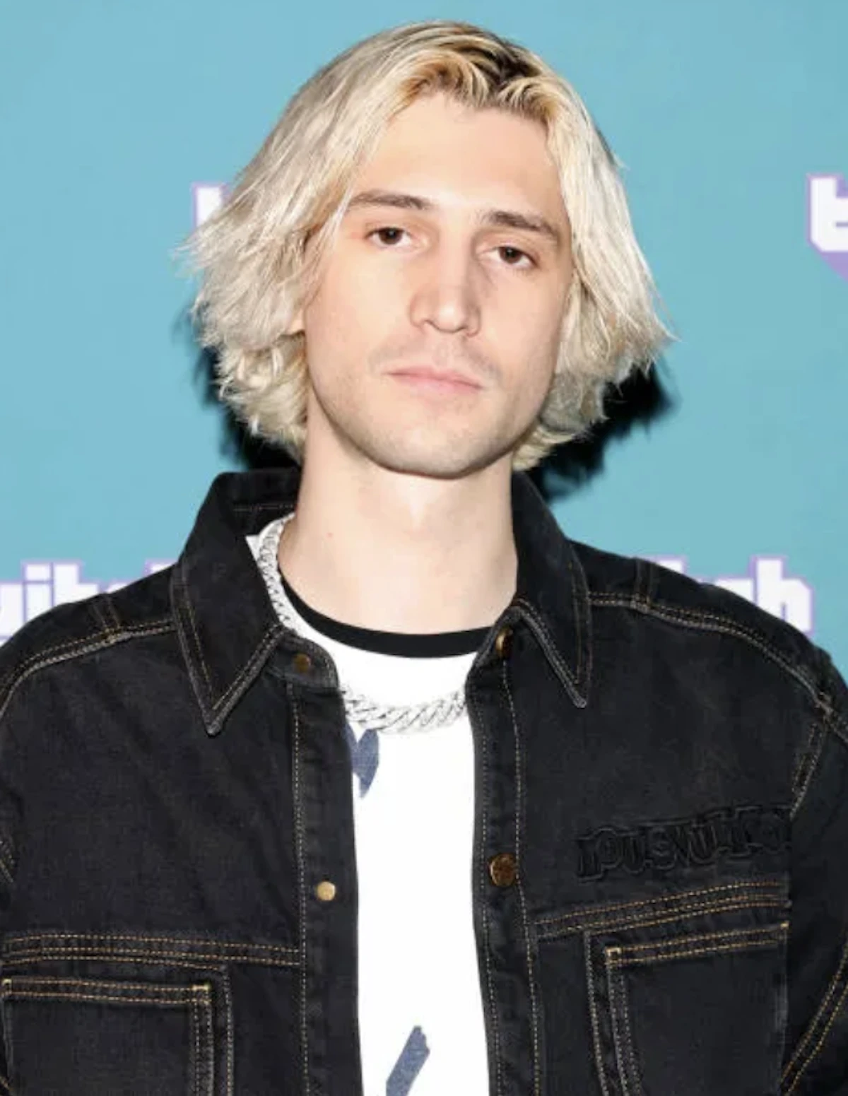 Portrait de xQc (F&eacute;lix Lengyel) lors d&rsquo;un &eacute;v&eacute;nement Twitch avec cheveux blonds et veste noire en denim